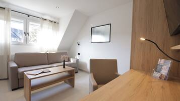 A modern living room with a sofa, a coffee table, a chair, and a wooden desk.