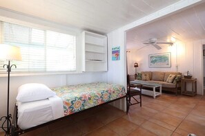 Quarto com cama, sofá, mesa e ventilador de teto.