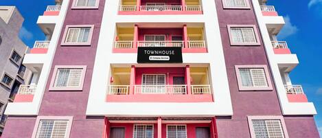 A multi-story building with balconies and a sign indicating it is a serviced apartment.
