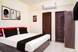 A hotel room with a bed, a wardrobe, a door, and three framed pictures on the wall. - Townhouse Oak Sankaramatam Road (Visakhapatnam)