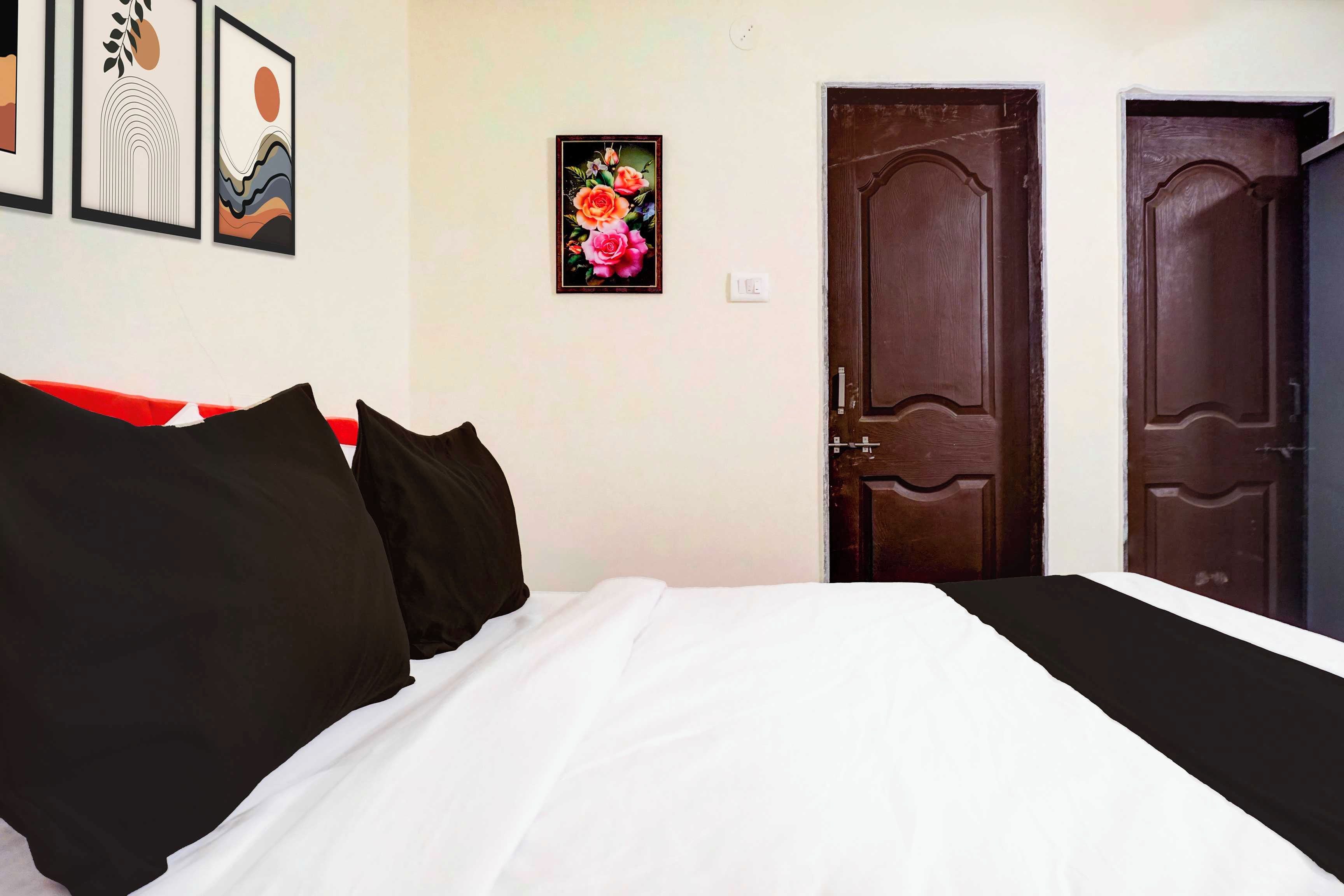 Un dormitorio con una cama, dos puertas y cuadros en la pared.
