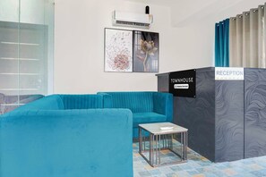 A reception area with a blue sofa, a small table, an air conditioning unit, and a sign indicating 'RECEPTION'. - Townhouse Oak Sankaramatam Road (Visakhapatnam)