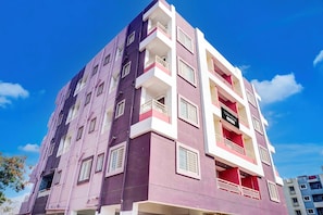 Un edificio de varios pisos con balcones, un letrero que indica que es una casa adosada y un cielo azul despejado al fondo.