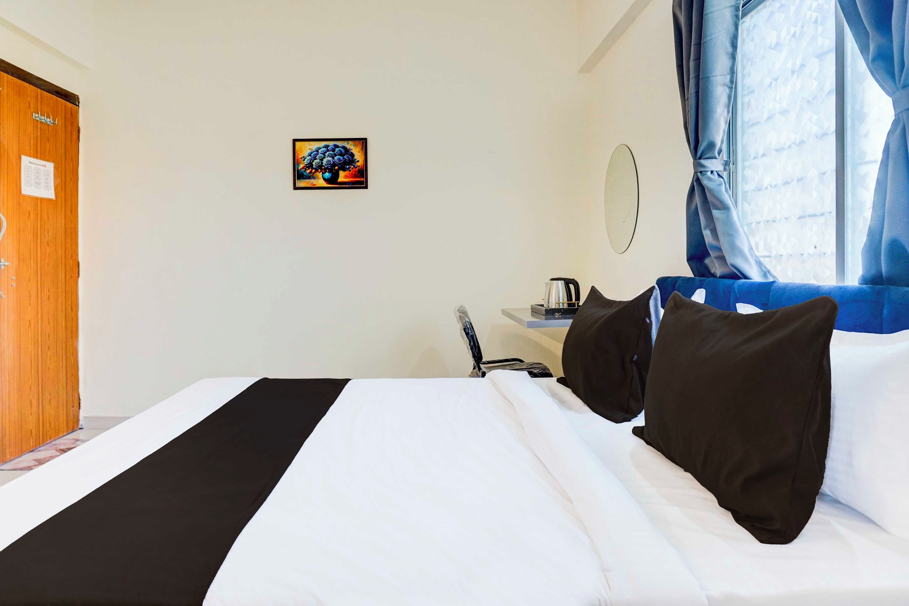 Una habitación de hotel con cama, escritorio con hervidor, espejo y puerta.