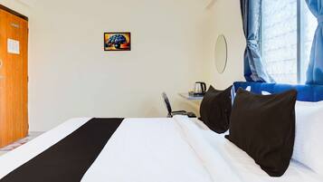 Ein Hotelzimmer mit einem Bett, einem Schreibtisch mit Wasserkocher, einem Spiegel und einer Tür.