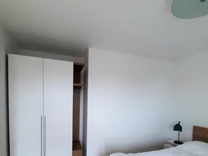 Ein Hotelzimmer mit einem Bett, einem Nachttisch, einer Lampe und einem Kleiderschrank.