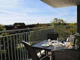 A balcony with a table set for dining, overlooking a residential area.