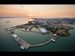 An aerial view of a coastal city with a marina, buildings, and a sunset. - Studio Near Darwin CBD With Rooftop BBQ (Darwin)