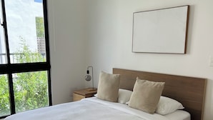 Une chambre à coucher avec un grand lit, une table de chevet, une lampe, un luminaire suspendu et un climatiseur fixé au mur.