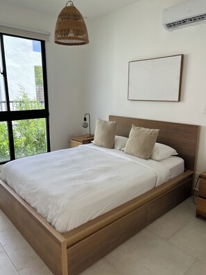Un dormitorio con una cama grande, una mesita de noche, una lámpara, un aplique y un aire acondicionado instalado en la pared.
