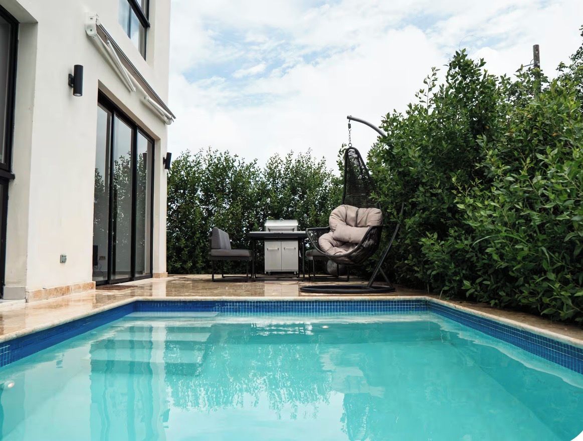 Una piscina con zona de patio, que incluye una silla y una mesa.