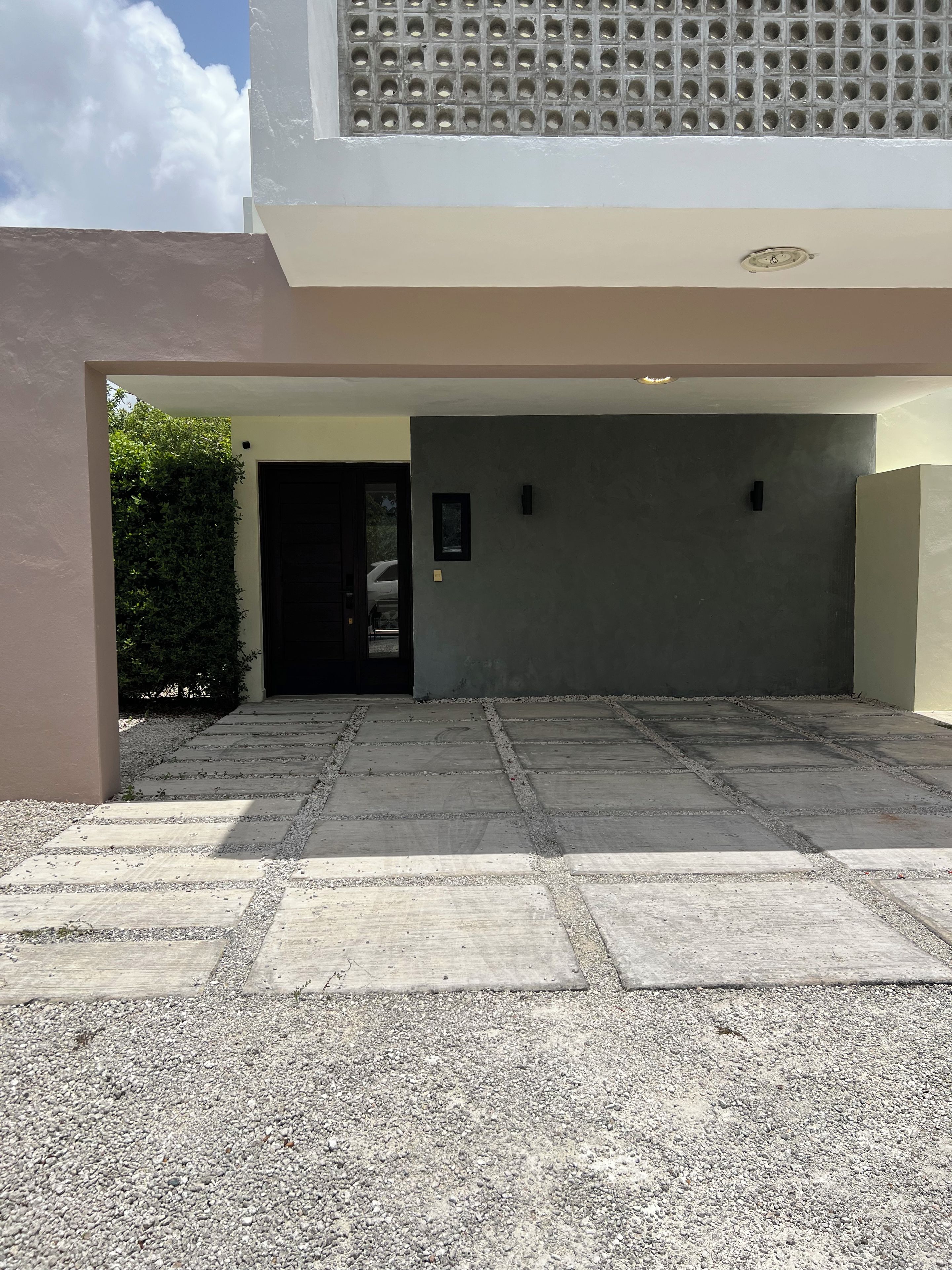 A building entrance with a paved driveway leading to a garage door.
