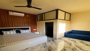 Un dormitorio con una cama, un ventilador de techo, un sofá azul y un piso de mármol.