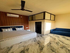 Un dormitorio con una cama, un ventilador de techo, un sofá azul y un piso de mármol.