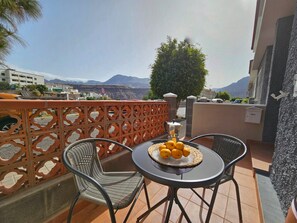 A balcony with a table, chairs, and a fruit basket. - Hoya del Viejo Duplex - Laaldeabnb (CN)