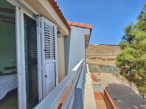 Een balkon met uitzicht op een glooiend landschap, een betegelde vloer en een balustrade.
