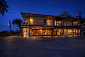 A two-story building with a flat roof, large windows, and a balcony on the upper floor.