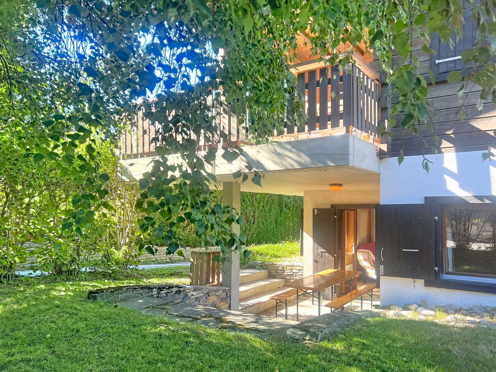 Un bâtiment à deux étages doté d’un balcon, d’un espace extérieur aménagé pour s’asseoir et d’un chemin en pierre.