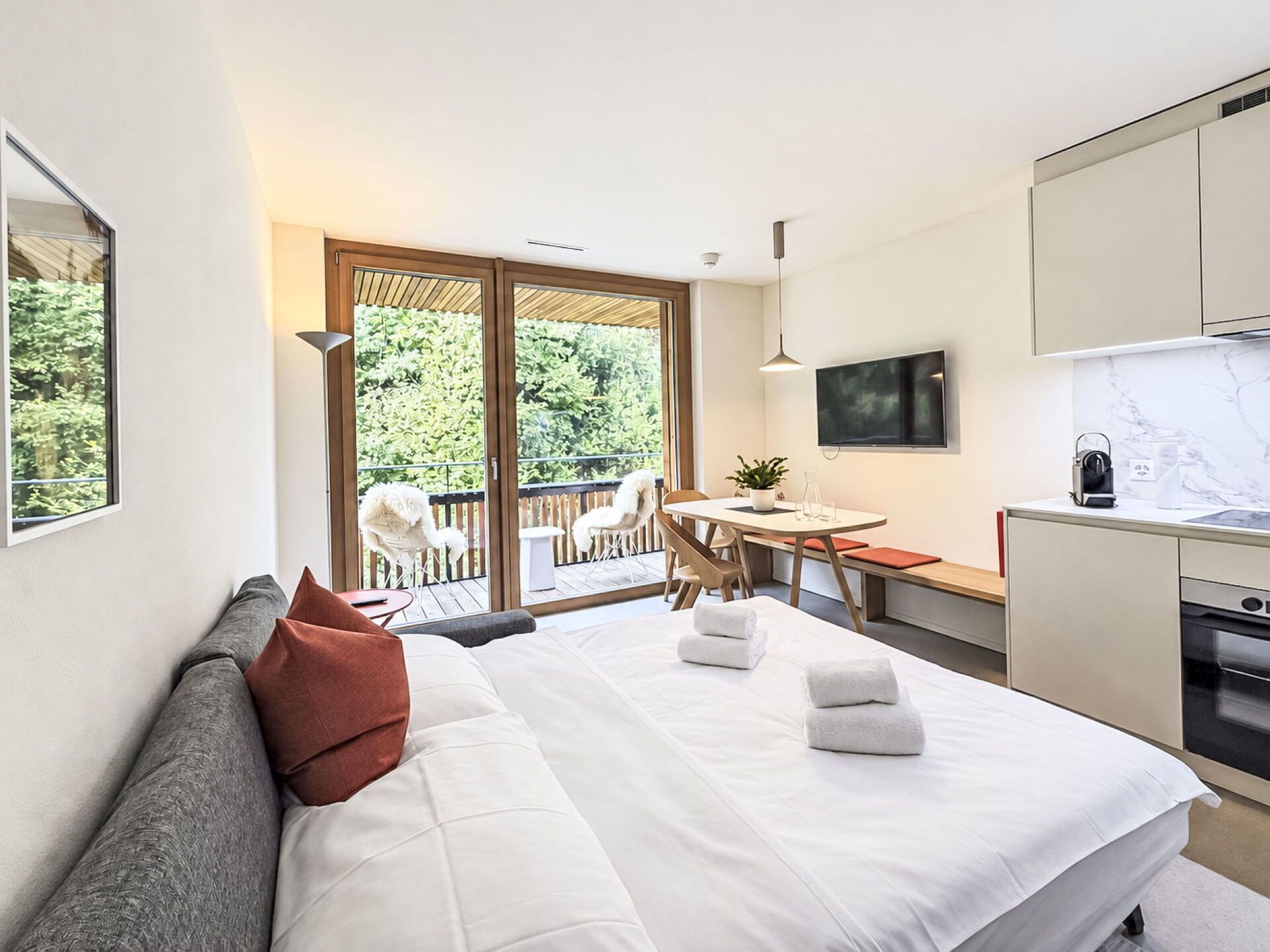 Une chambre d’hôtel moderne équipée d’un lit, d’un bureau, d’une télévision et d’un coin cuisine.