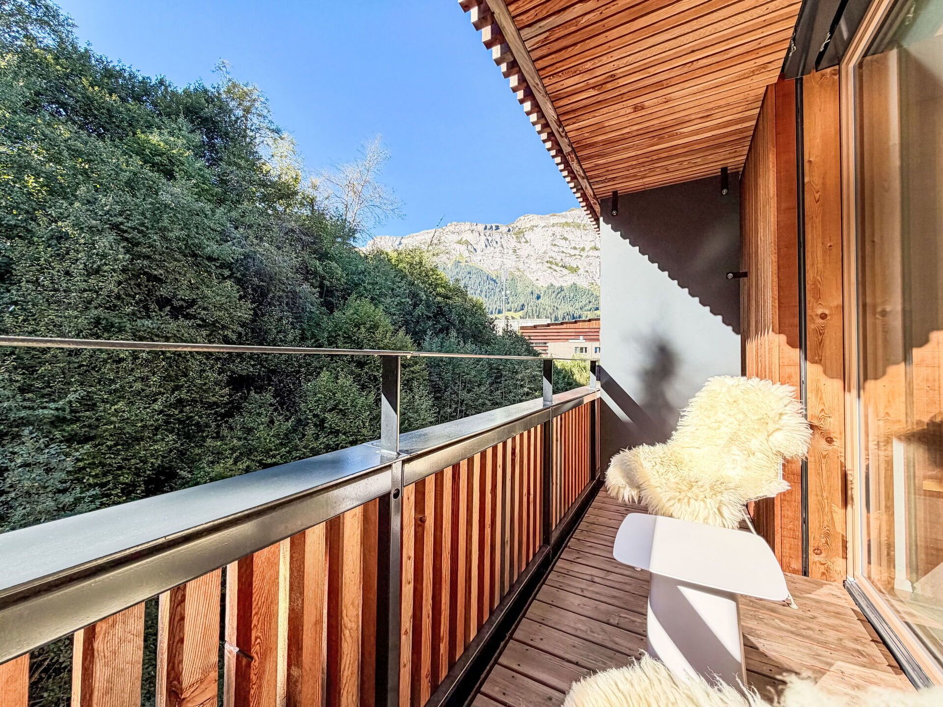A wooden balcony with a view of a forested mountain.