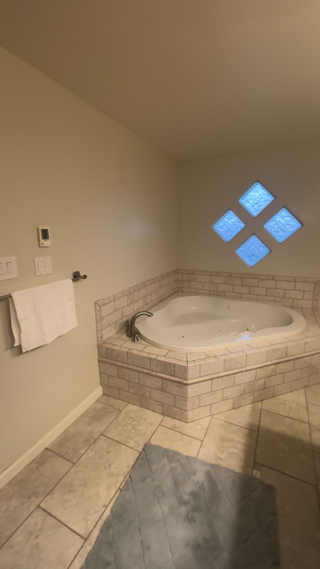 A bathroom with a freestanding bathtub, a towel rack, and a window with a diamond pattern.