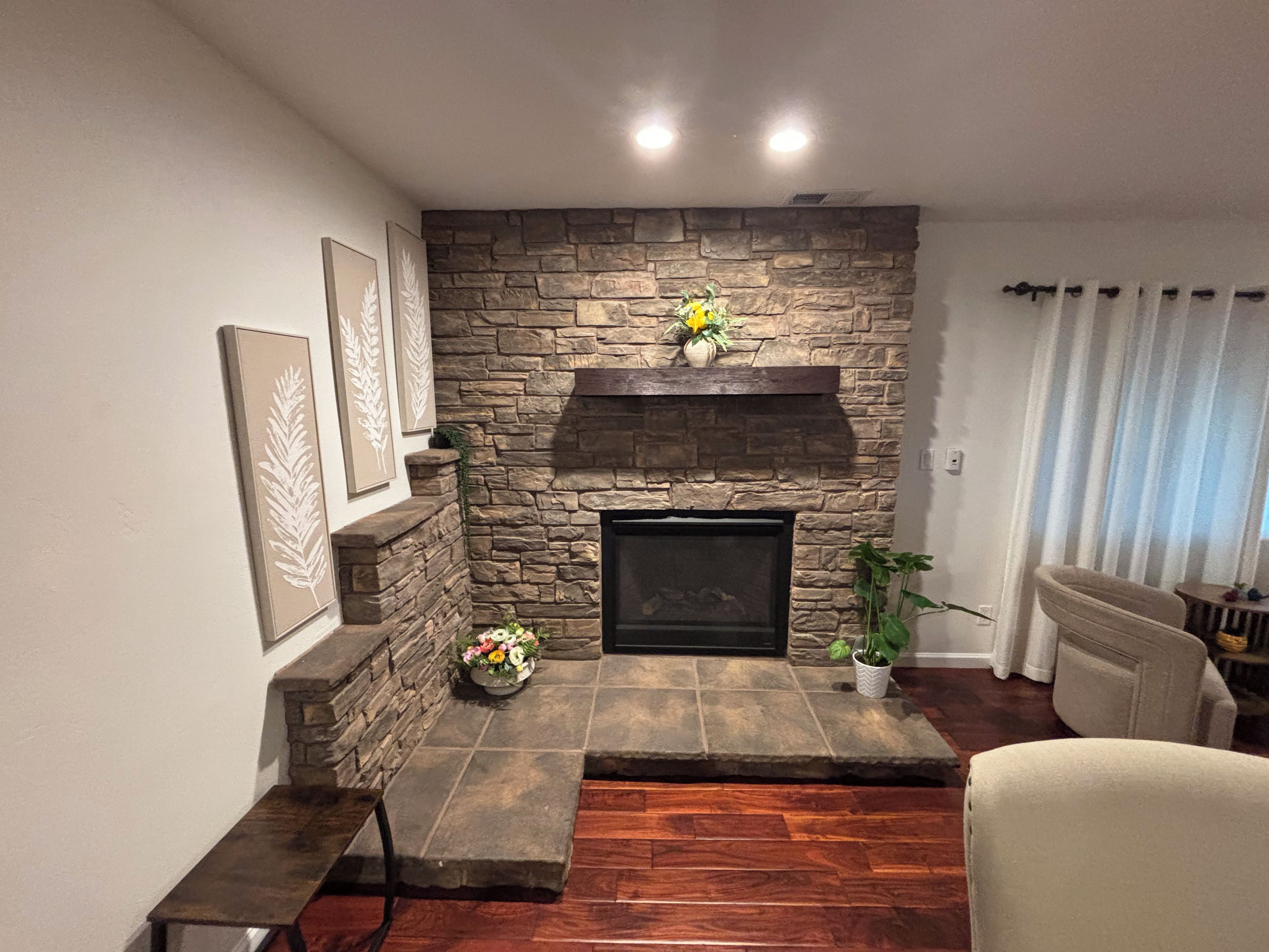 Una sala de estar con chimenea de piedra, un banco y una planta en maceta.