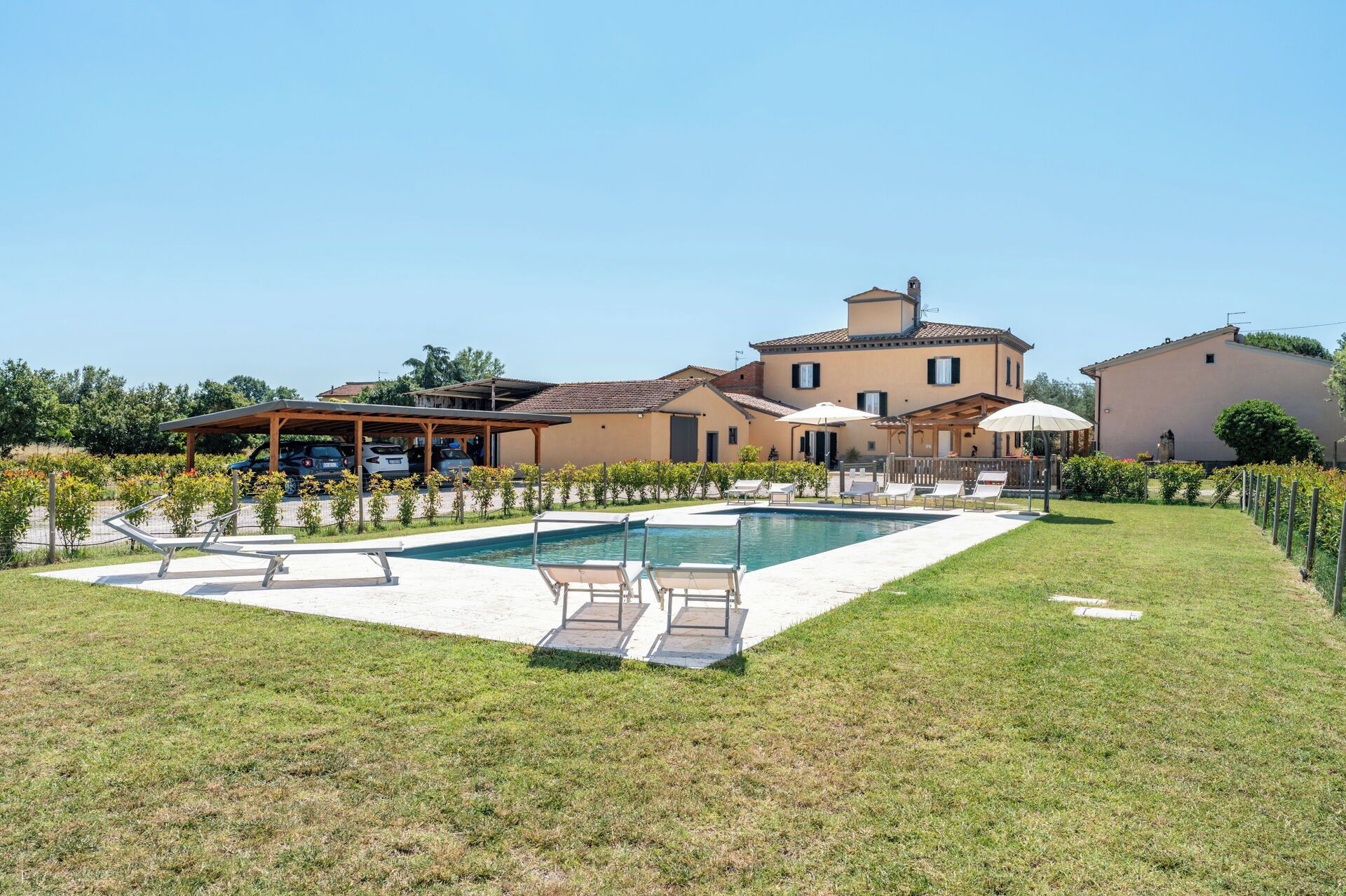 Eine Villa mit Schwimmbad, Sitzgelegenheiten im Freien und einem überdachten Bereich.