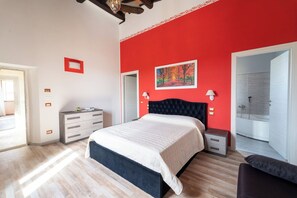 Ein Schlafzimmer mit Bett, Nachttischen, einem Kleiderschrank, einer roten Akzentwand und einem Gemälde.