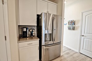 A kitchen with a stainless steel refrigerator, a coffee maker, and a mug holder on the countertop. - Beautiful OVBC townhouse steps from the Amenities! Wifi, Pool, Fitness Center, Sauna, Weekend Shuttle! (Ocean View)