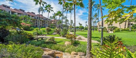 A resort with a well-maintained garden, palm trees, and a clear blue sky.