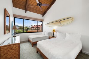 A hotel room with two beds, a ceiling fan, a large window with a view, and a surfboard mounted on the wall. - Top-Floor With Views I Kamaole Sands 6410 (Kihei)