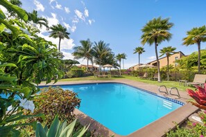 A swimming pool with a tiled edge, surrounded by palm trees and a clear sky. - Remodeled Ocean View | Wailea Ekolu 703 (Wailea)