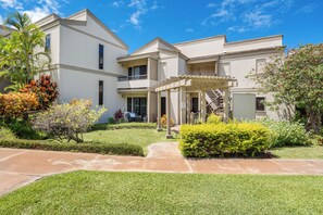 A two-story residential building with a covered patio and a well-maintained lawn. - Remodeled Ocean View | Wailea Ekolu 703 (Wailea)
