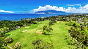A golf course with a view of the ocean and a mountain in the distance. - Remodeled Ocean View | Wailea Ekolu 703 (Wailea)