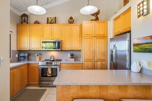 A kitchen with wooden cabinets, stainless steel appliances, and a granite countertop. - Ocean View Wailea 2bd I Wailea Ekolu 702 (Kihei)
