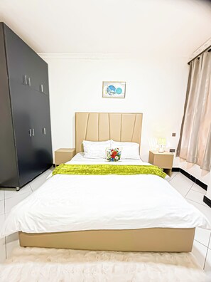 Ein Hotelzimmer mit Bett, Nachttisch, Lampe, Schrank und einem gerahmten Bild an der Wand.
