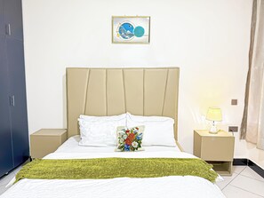 Ein Hotelzimmer mit Bett, Nachttisch, Lampe und einem gerahmten Bild an der Wand.