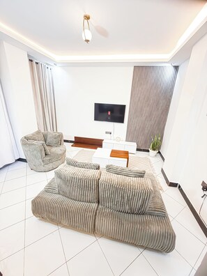 Ein modernes Wohnzimmer mit einem Ecksofa, einem an der Wand befestigten Fernseher und einem Deckenventilator.