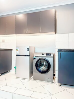 Ein Waschraum mit einer Waschmaschine, einem Kühlschrank und einem Gefriertruhe.
