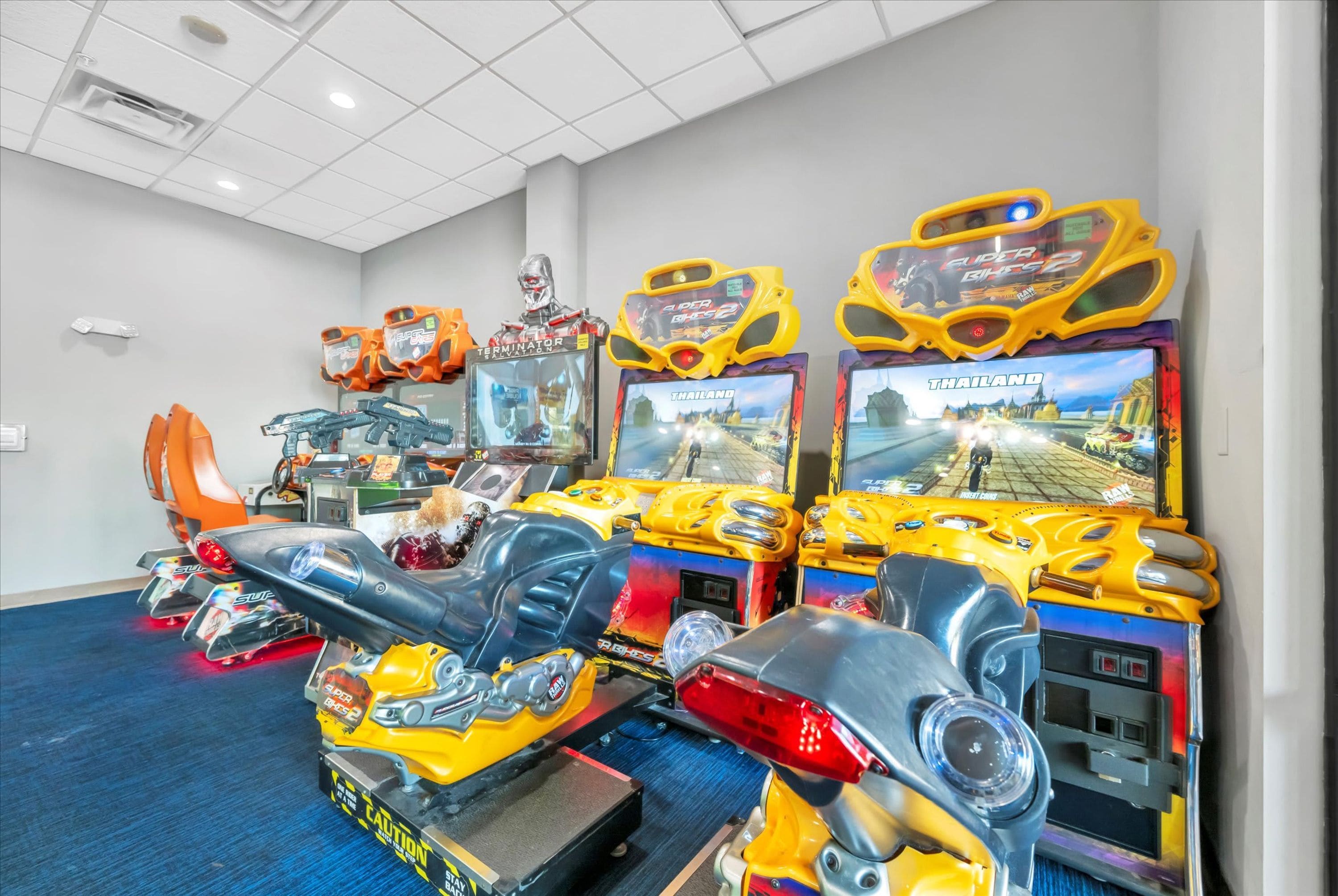 Eine Reihe von Spielautomaten in einem Raum mit blauem Teppich und weißen Wänden.