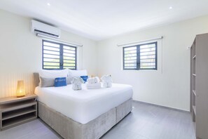Ein Hotelzimmer mit Bett, zwei Fenstern, einer Klimaanlage, einer Nachttischlampe und einem Kleiderschrank.