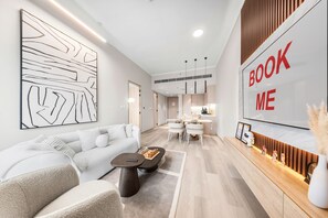 A modern hotel lobby with a sofa, coffee table, and a dining area. - Stayshort - Amazing 1 Bedroom in Concept 7 JVC Sleeps 2 (Dubai)