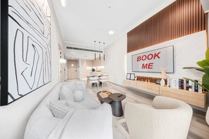 A modern living room with a sofa, a coffee table, and a dining area with a table and chairs. - Stayshort - Amazing 1 Bedroom in Concept 7 JVC Sleeps 2 (Dubai)