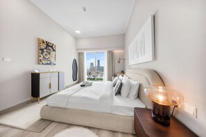 A modern hotel room with a large bed, a desk, and a view of the cityscape. - Stayshort - Amazing 1 Bedroom in Concept 7 JVC Sleeps 2 (Dubai)