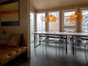 A modern interior with a wooden ceiling, a dining table with chairs, and a sofa. - Cabin in Turrach With Sauna and Wi-fi (Stadl-Predlitz)