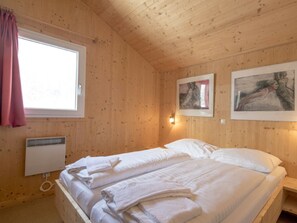 A wooden-paneled room with a bed, a window, and artwork on the wall. - Cabin in Turrach With Sauna and Wi-fi (Stadl-Predlitz)