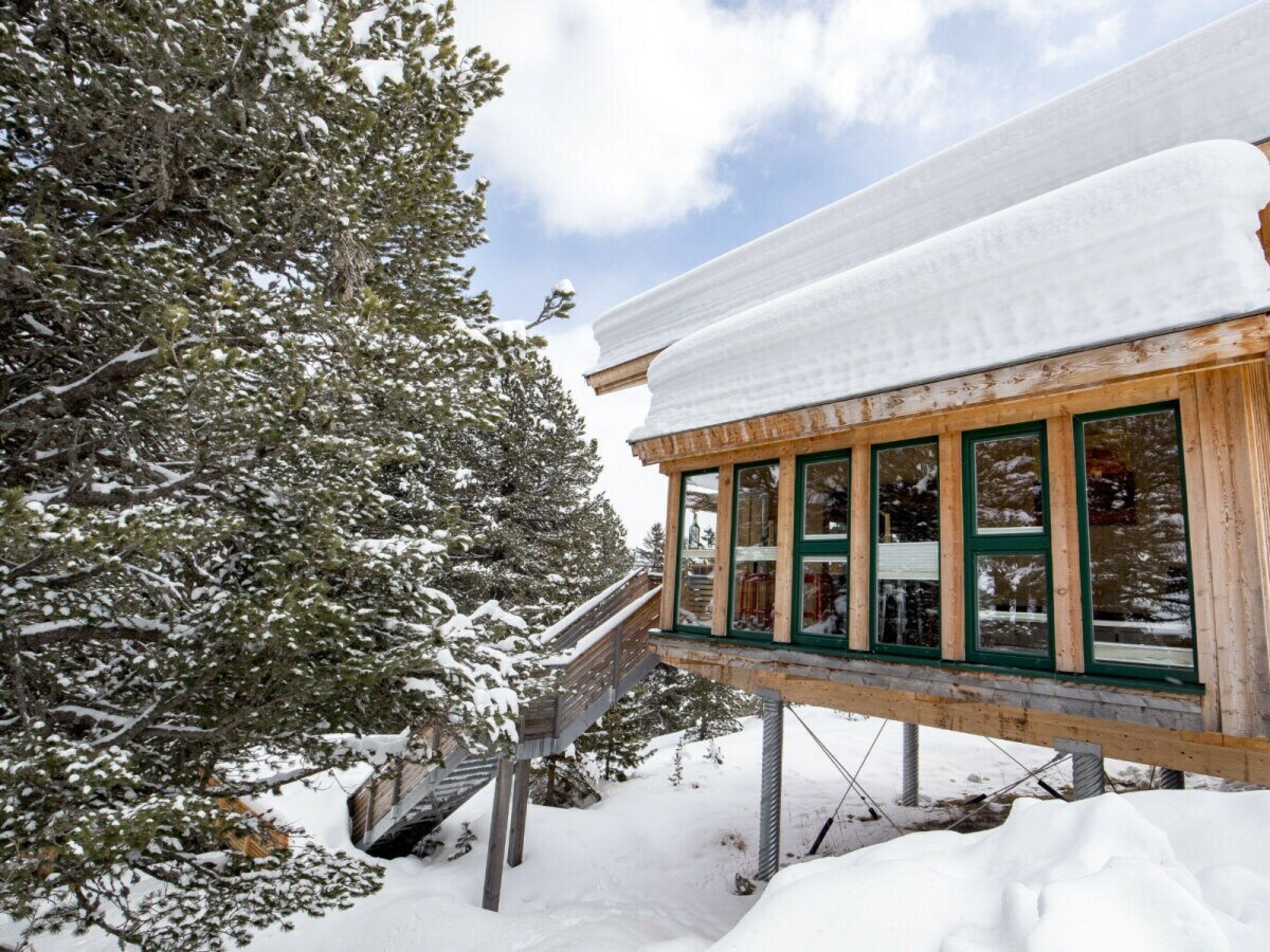 A wooden building with a snow-covered roof and a glass facade.