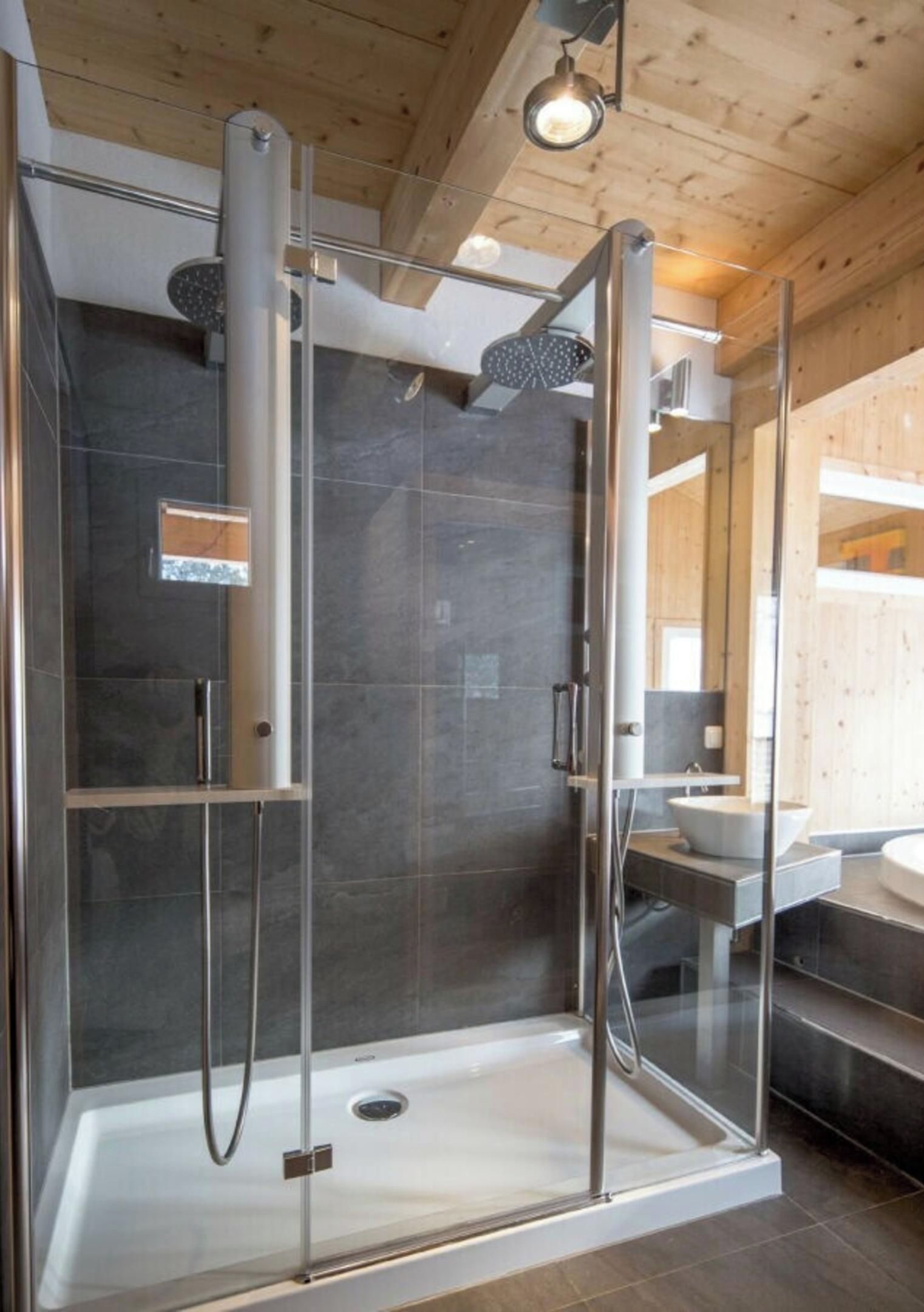 Une cabine de douche moderne dotée de portes en verre, d’un pommeau de douche apparent et d’un panneau de commande.