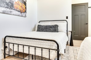 Ein Schlafzimmer mit einem Bett, einer Tür und einem Bild an der Wand.