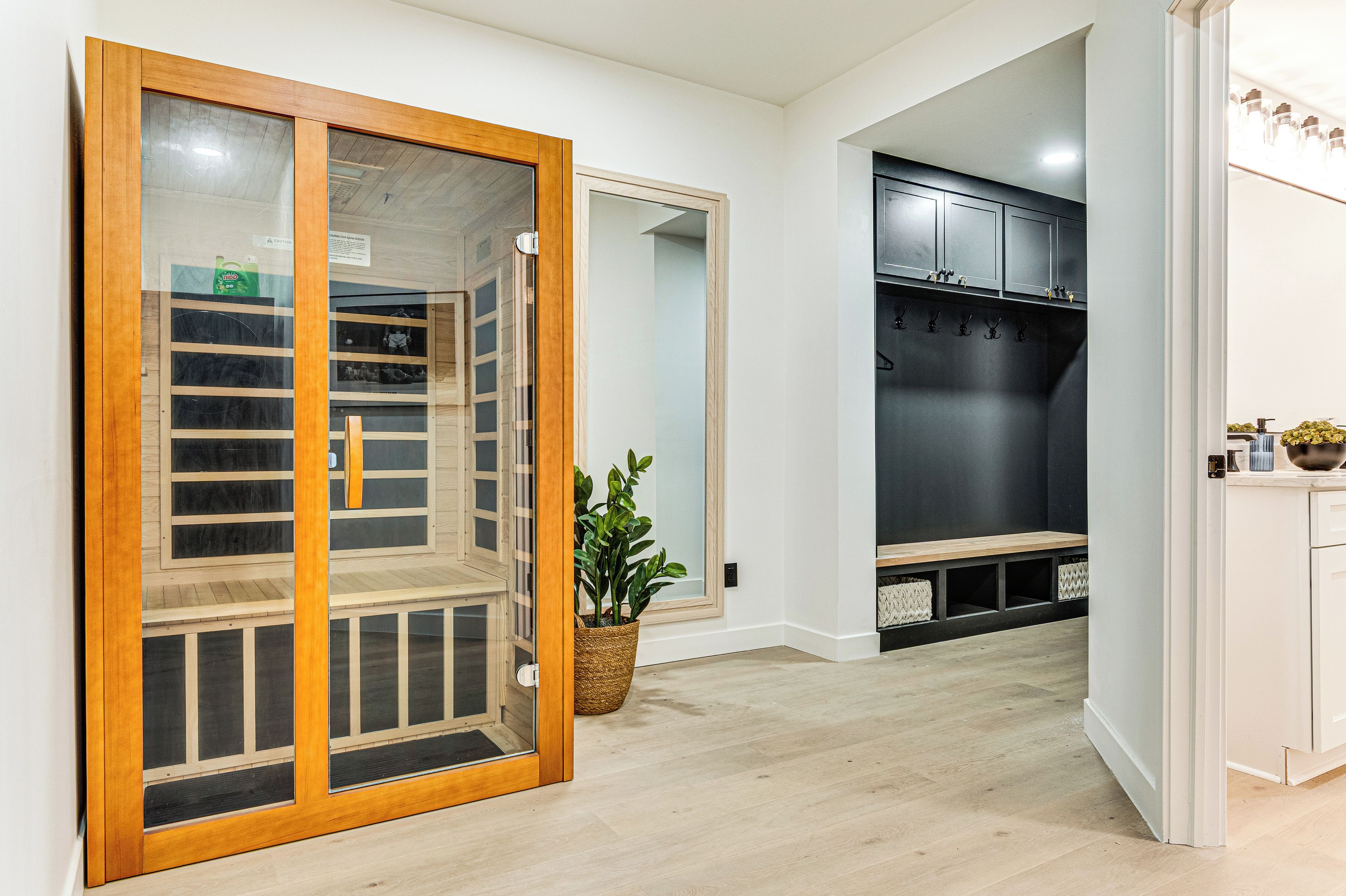 Una habitación con puerta de vidrio corredera, una planta en maceta, un banco y un perchero.